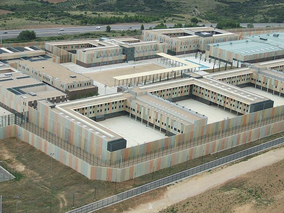 "Vista aérea del Centro Penitenciario Puig de les Basses, formado por varios edificios de baja altura agrupados alrededor de patios interiores y rodeados por un perímetro vallado."